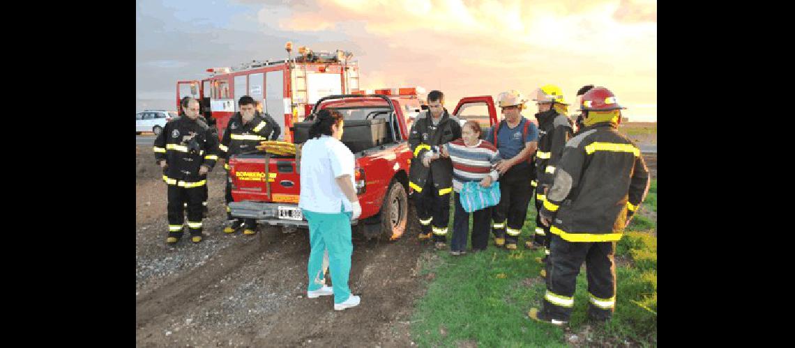 Los bomberos voluntarios ayudan a una de las ocupantes del auto a subir a la ambulancia 