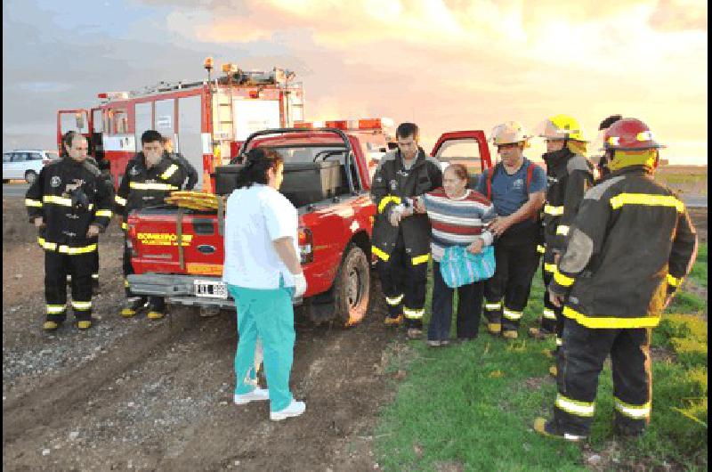 Los bomberos voluntarios ayudan a una de las ocupantes del auto a subir a la ambulancia 